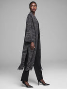 Long black and white tweed jacket with fringe hem and vertical slits.