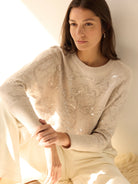 Light beige crew neck sweater with intricate floral embroidery detailed with shimmering silver sequins.