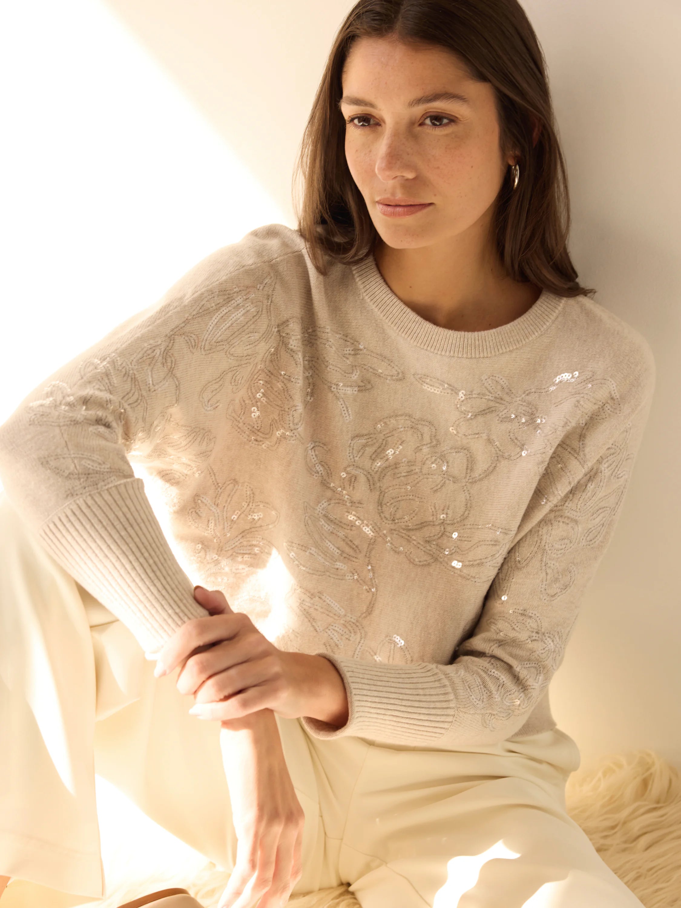 Light beige crew neck sweater with intricate floral embroidery detailed with shimmering silver sequins.