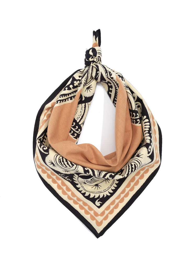 Folded bandana tied at top. Cream, black, and tan bohemian print with intricate designs and scalloped borders.