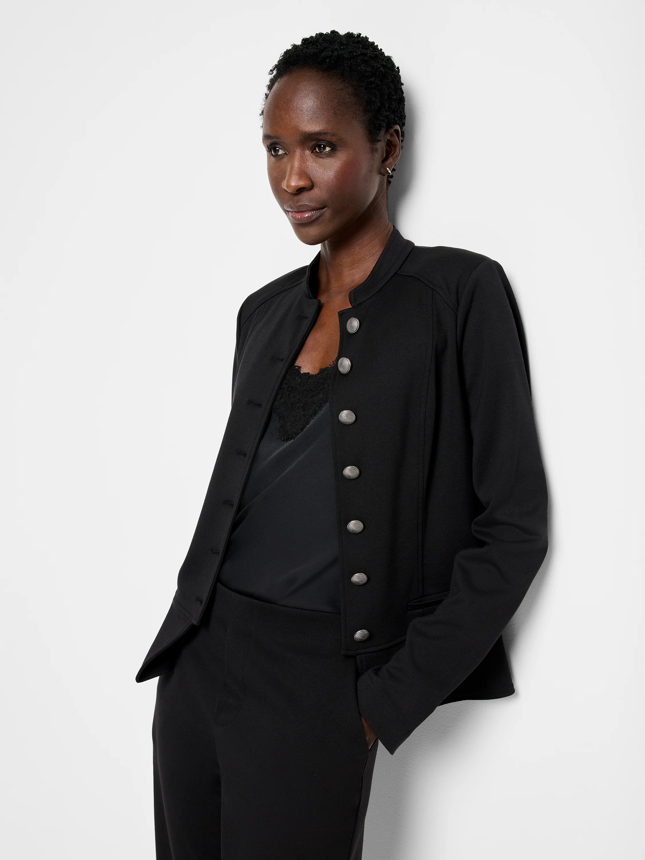 Black knit jacket with band collar, tailored fit, and decorative silver buttons down the front.