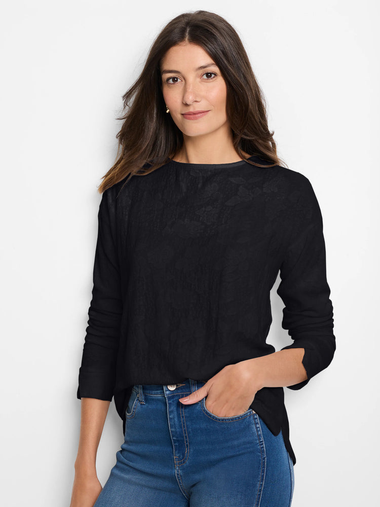 Black long-sleeve tee with a subtle, all-over lace knit texture and wide neckline, worn by a woman.