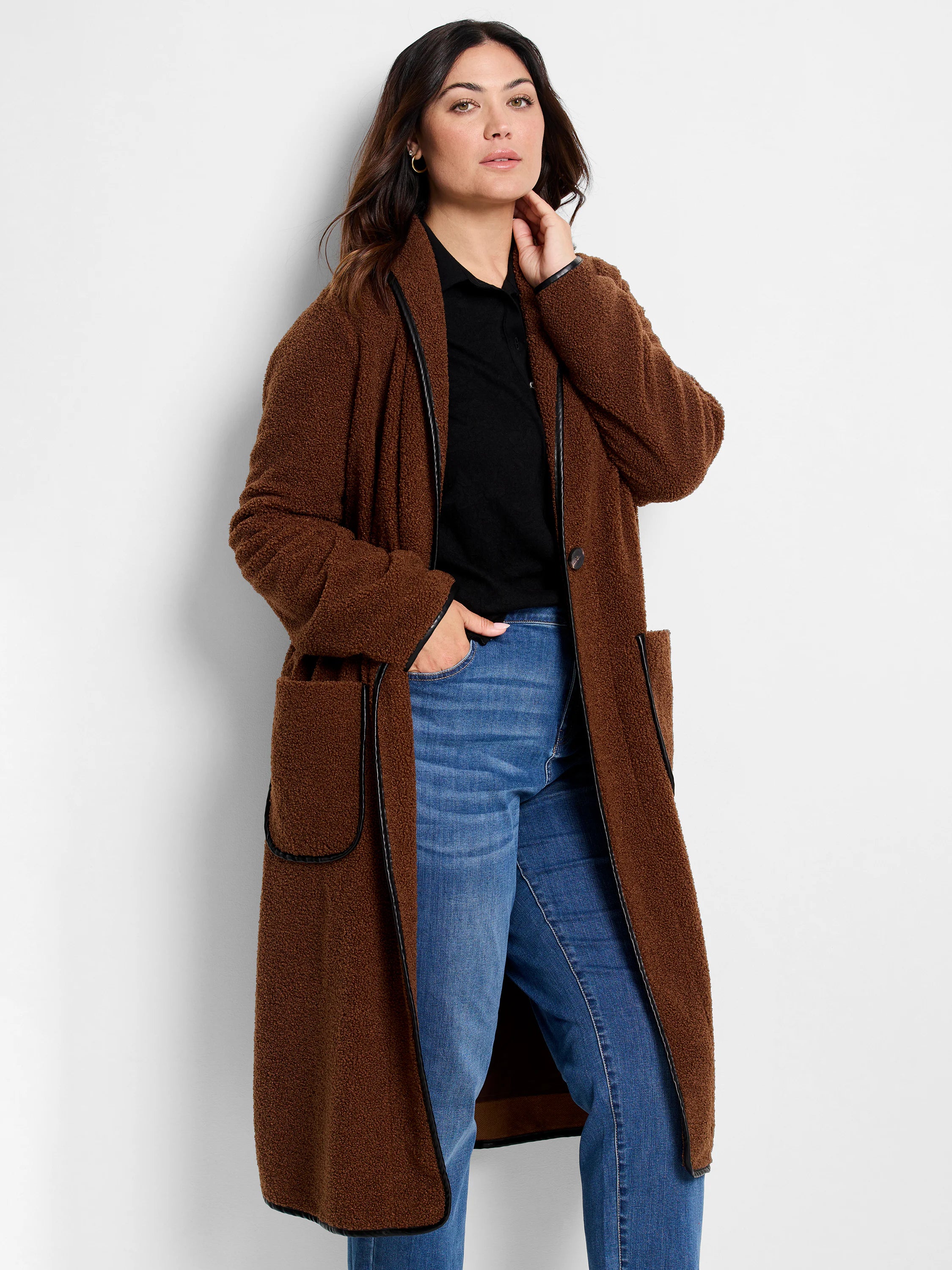 Brown fuzzy teddy coat with black trim on the collar, edges, and pockets. It is long and open-front.