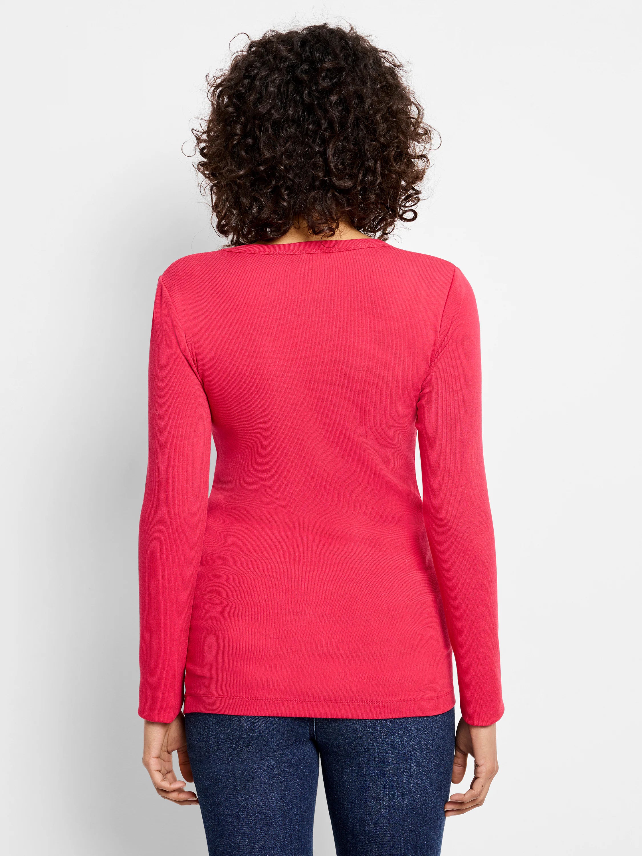 Back view of a bright pink ribbed long sleeve tee on a model. Features a close-knit vertical ribbed texture.