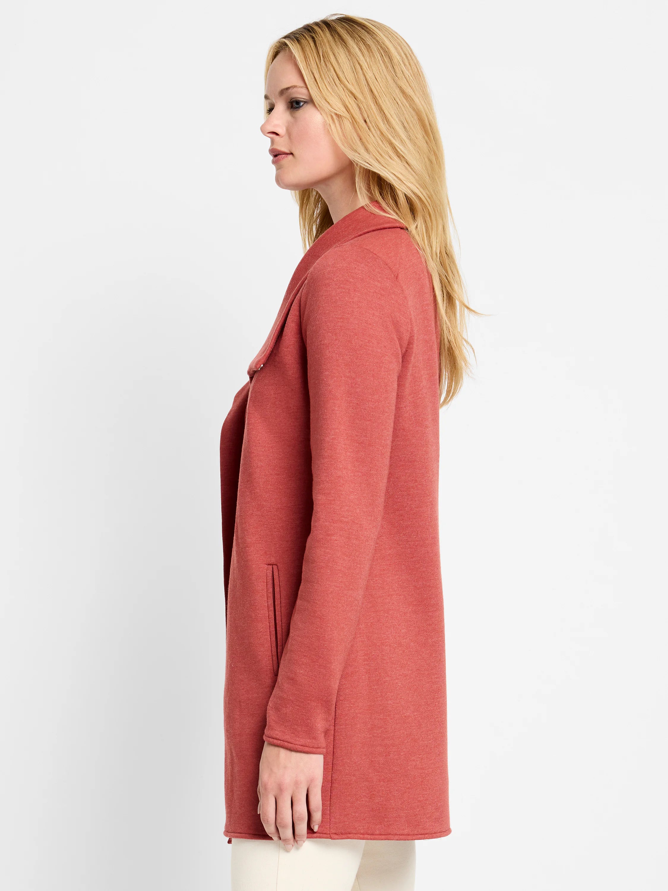 Rust-colored open jacket with long sleeves, wide draped lapels, and a side pocket. It extends past the hips.