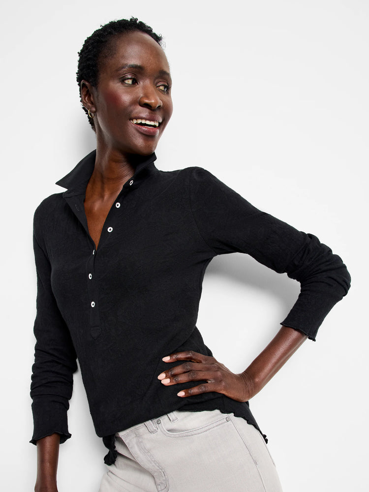 Black lace knit collared top with white buttons, long sleeves, and ruffled cuffs/hem.