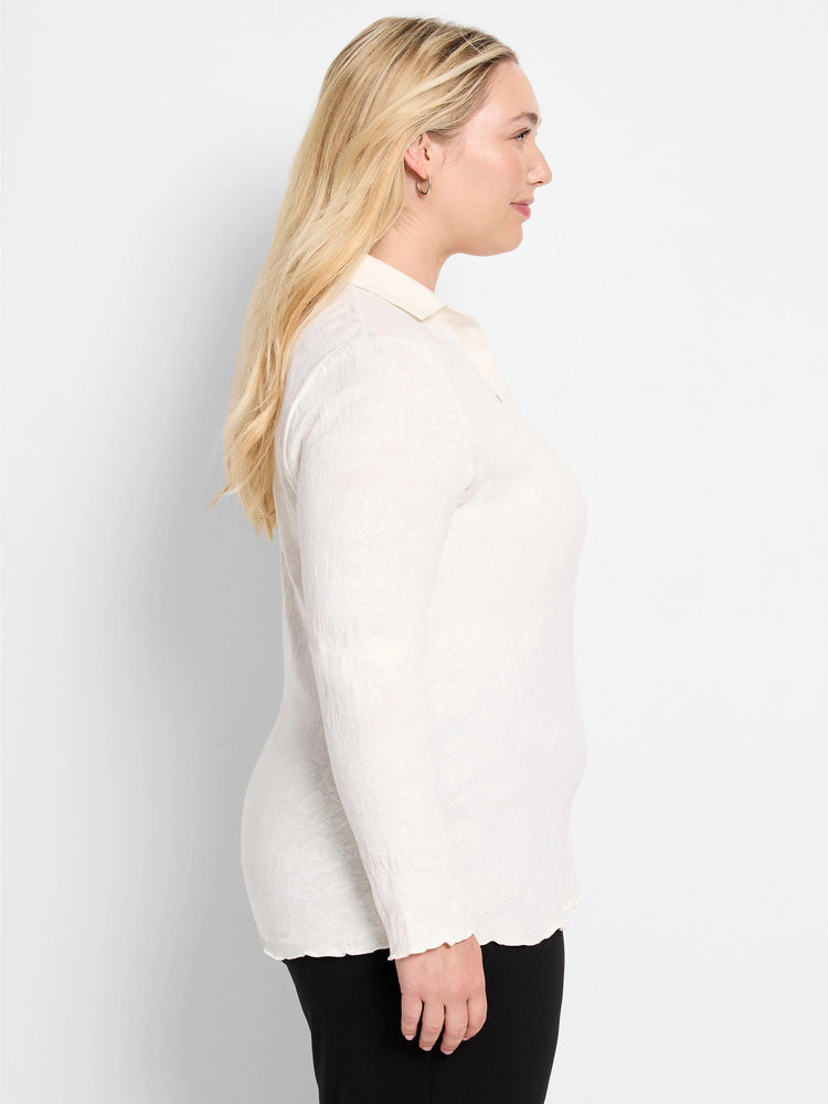 Off-white lace knit collared top with a subtle floral pattern, long sleeves, and scalloped edges. Model in profile.