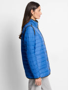 Vibrant blue sleeveless puffer vest with horizontal quilting, dark trim, and front snap buttons.