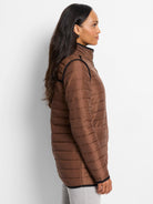 Brown side of reversible puffer jacket. Horizontally quilted, with a stand collar and black piping on edges.