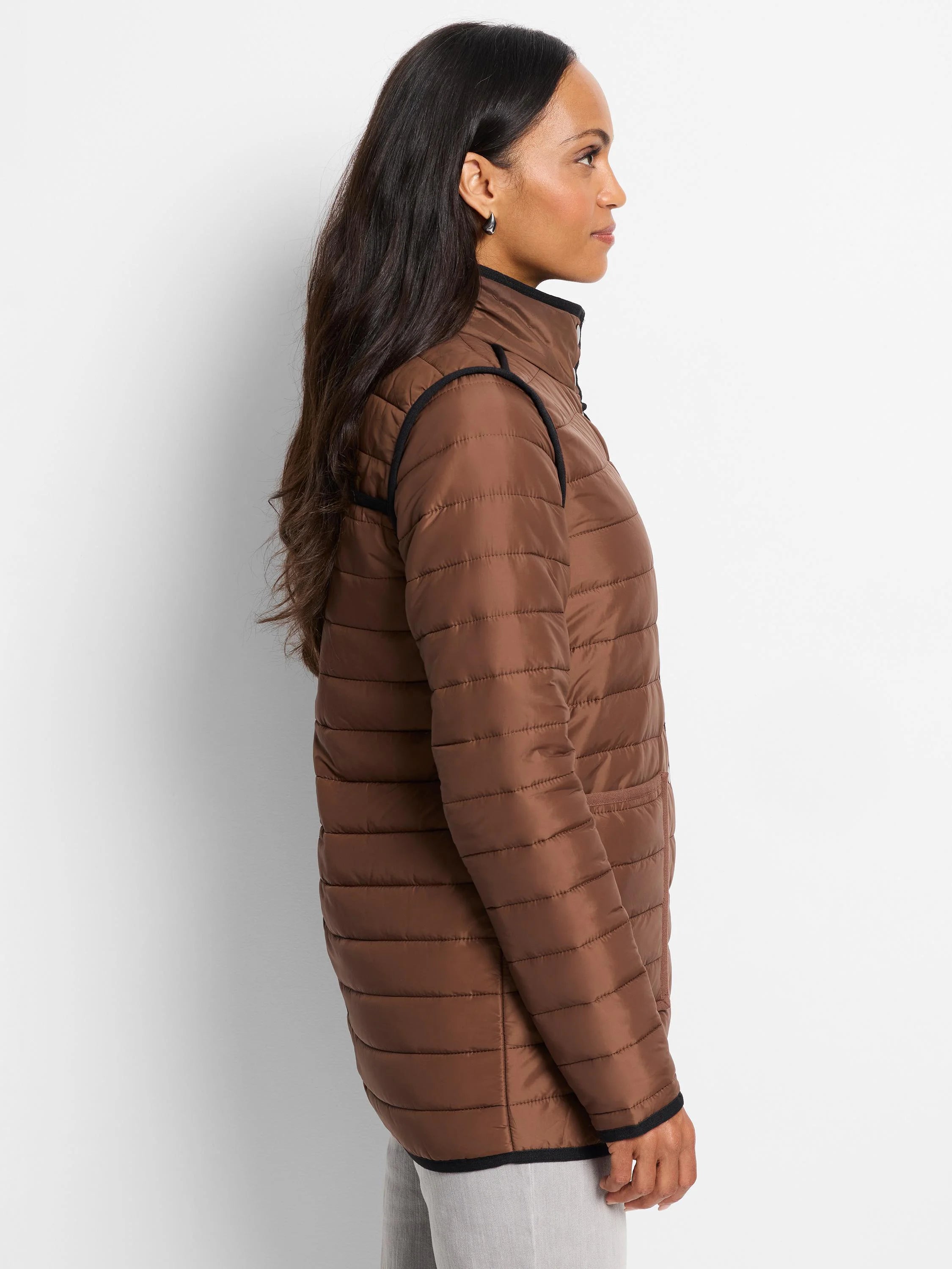 Brown side of reversible puffer jacket. Horizontally quilted, with a stand collar and black piping on edges.