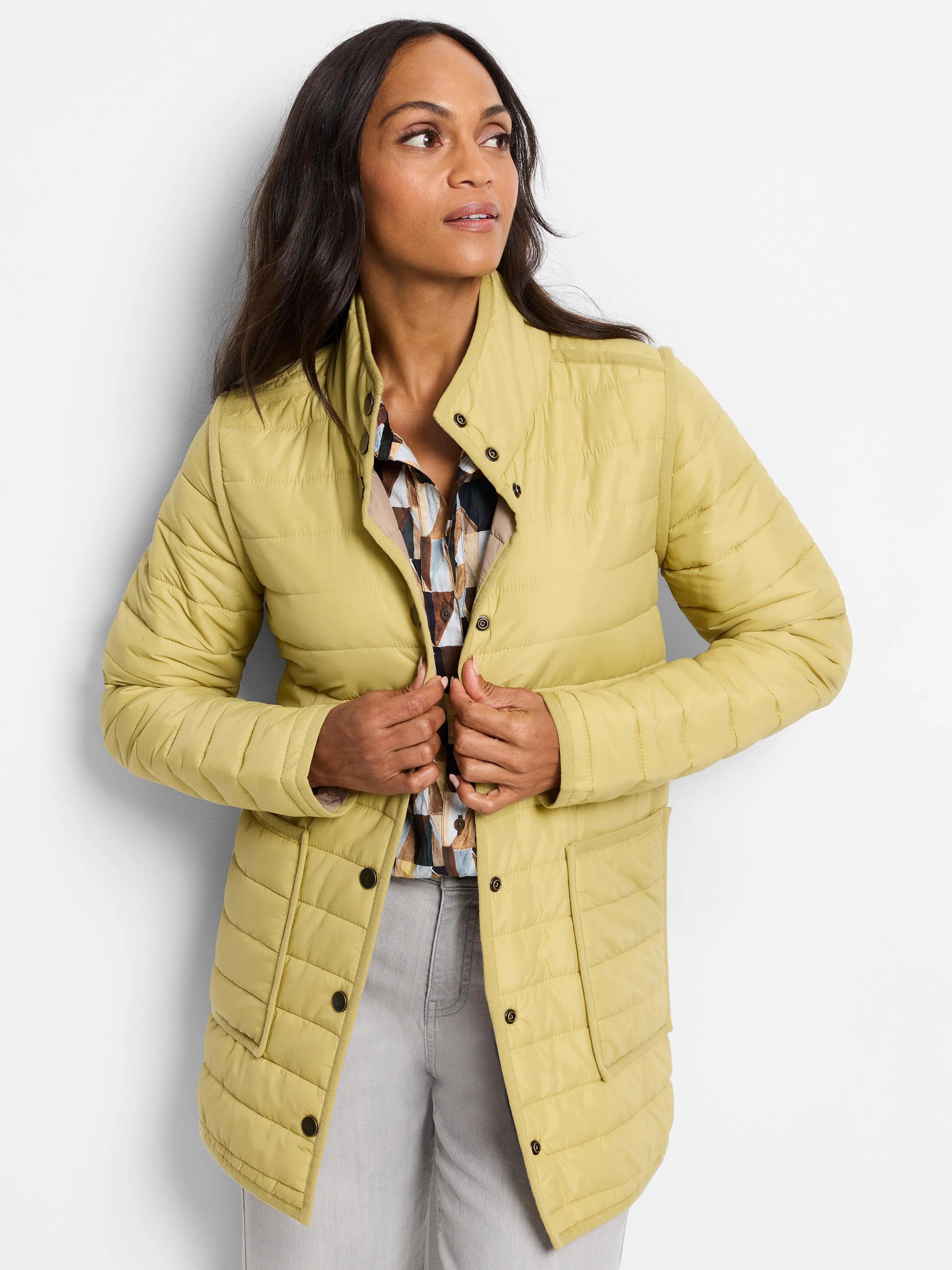 Light yellow reversible puffer jacket with a stand collar, snap buttons, and front pockets. Patterned lining.