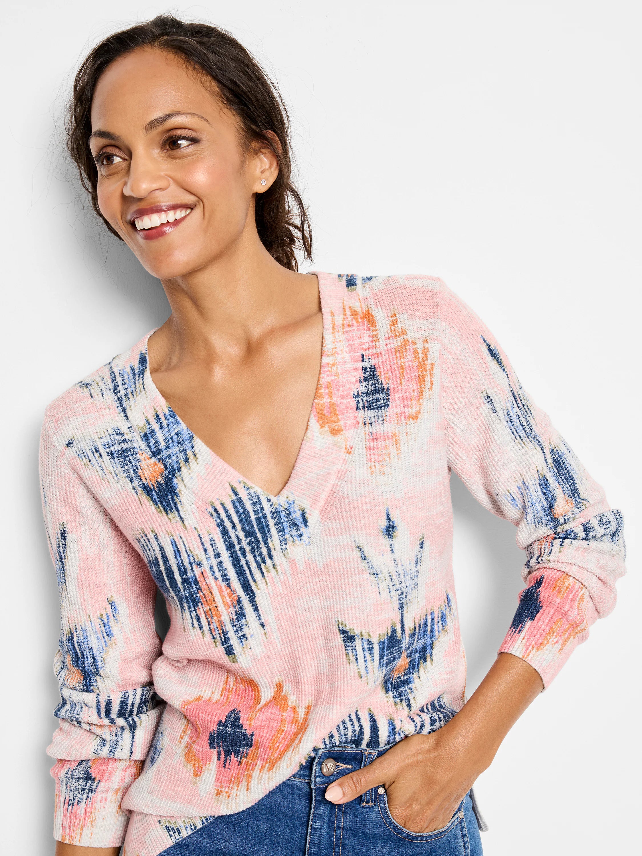 Pink waffle-knit V-neck sweater with abstract blue, white, and orange brushstroke pattern.