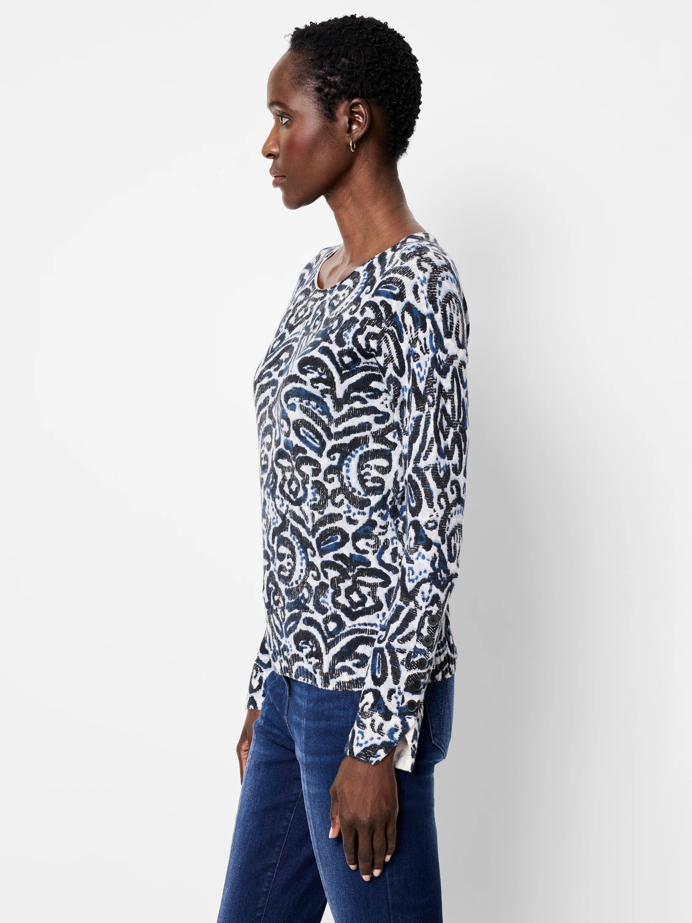 White sweater with black & blue abstract paisley print, crew neck, long sleeves with button cuffs.