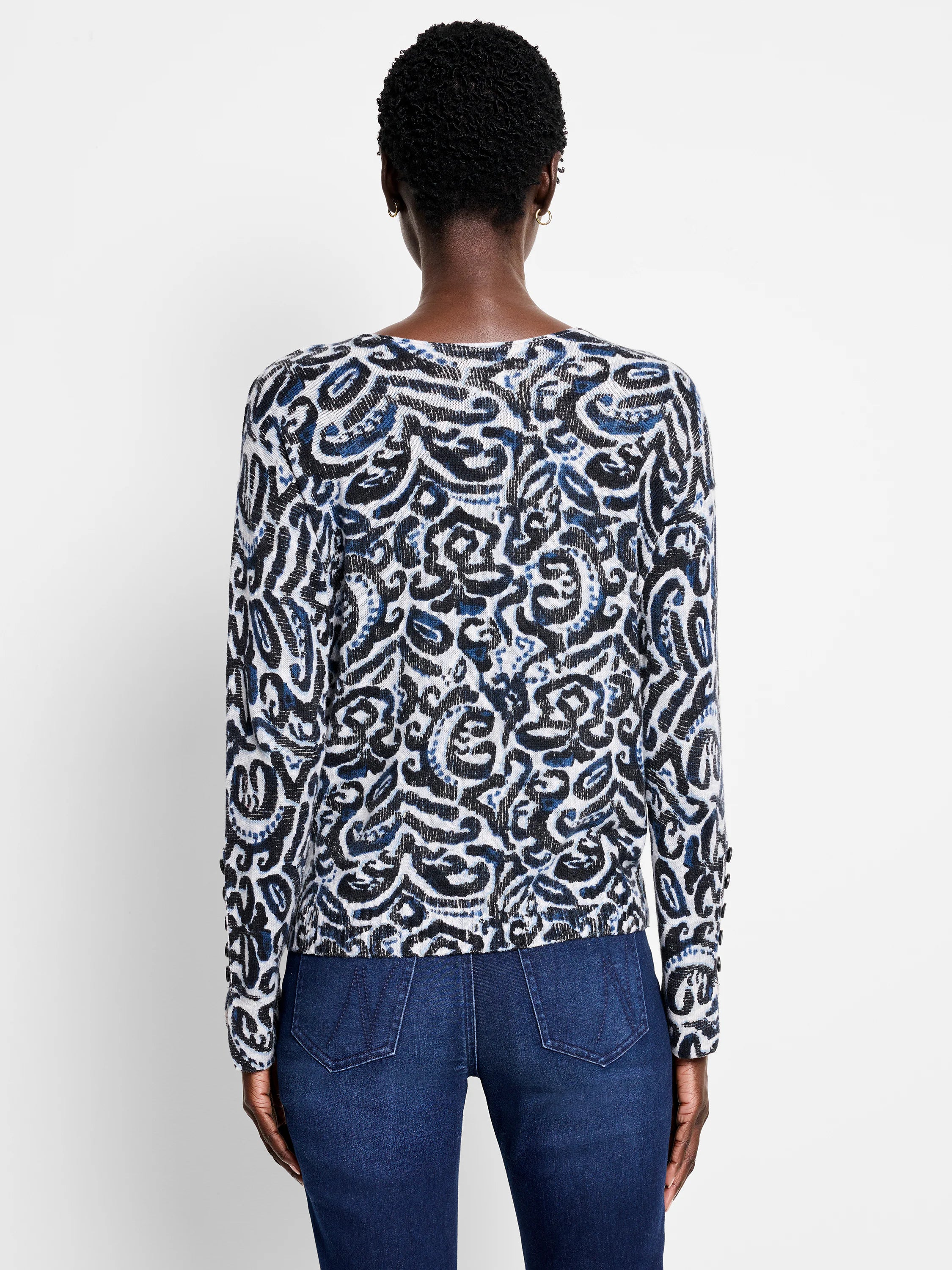 White sweater with a tossed paisley pattern in black and blue, worn by a model viewed from the back.