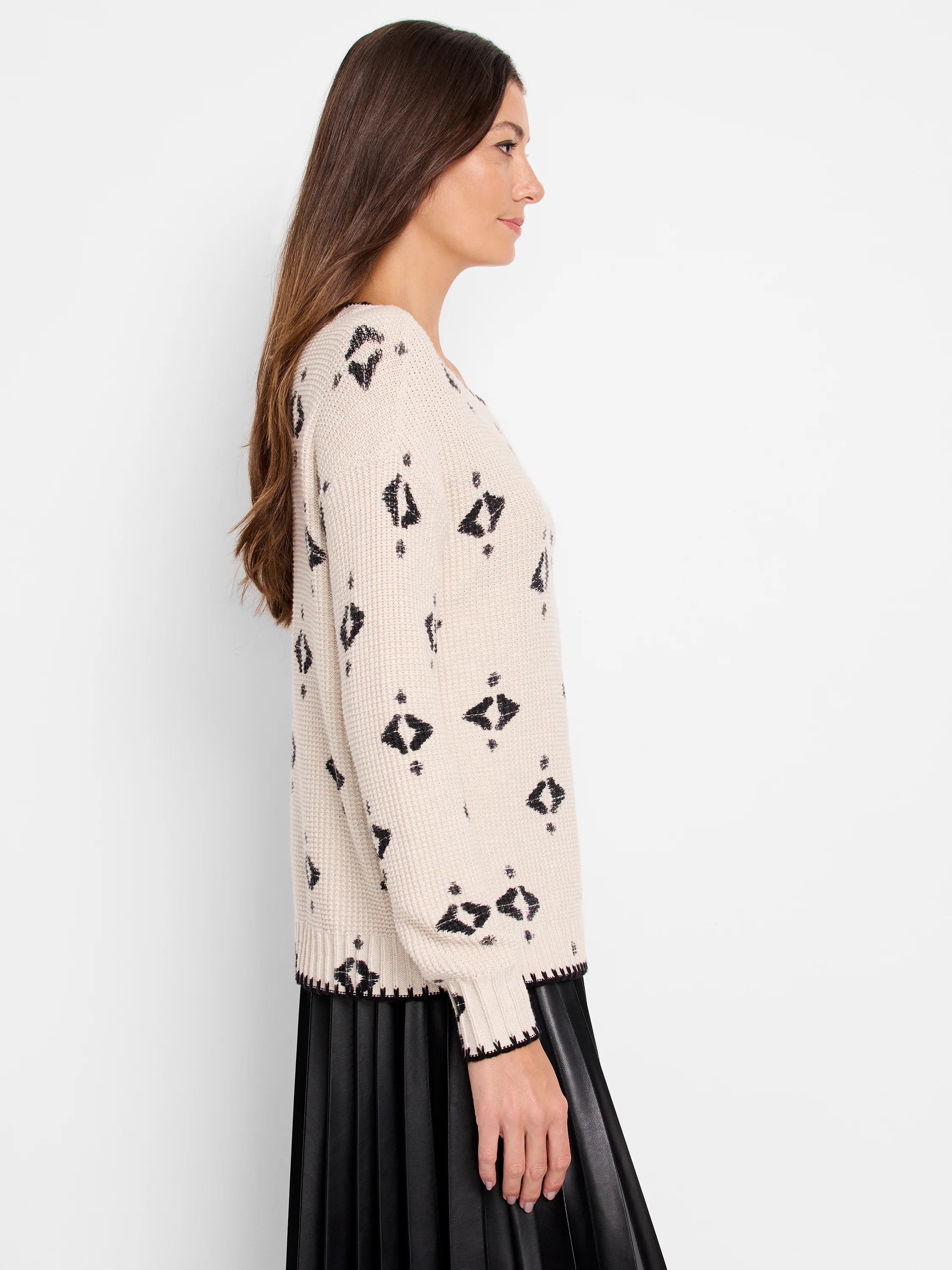 Cream knit sweater with black scattered geometric shapes. Ribbed cuffs and hem feature black trim.