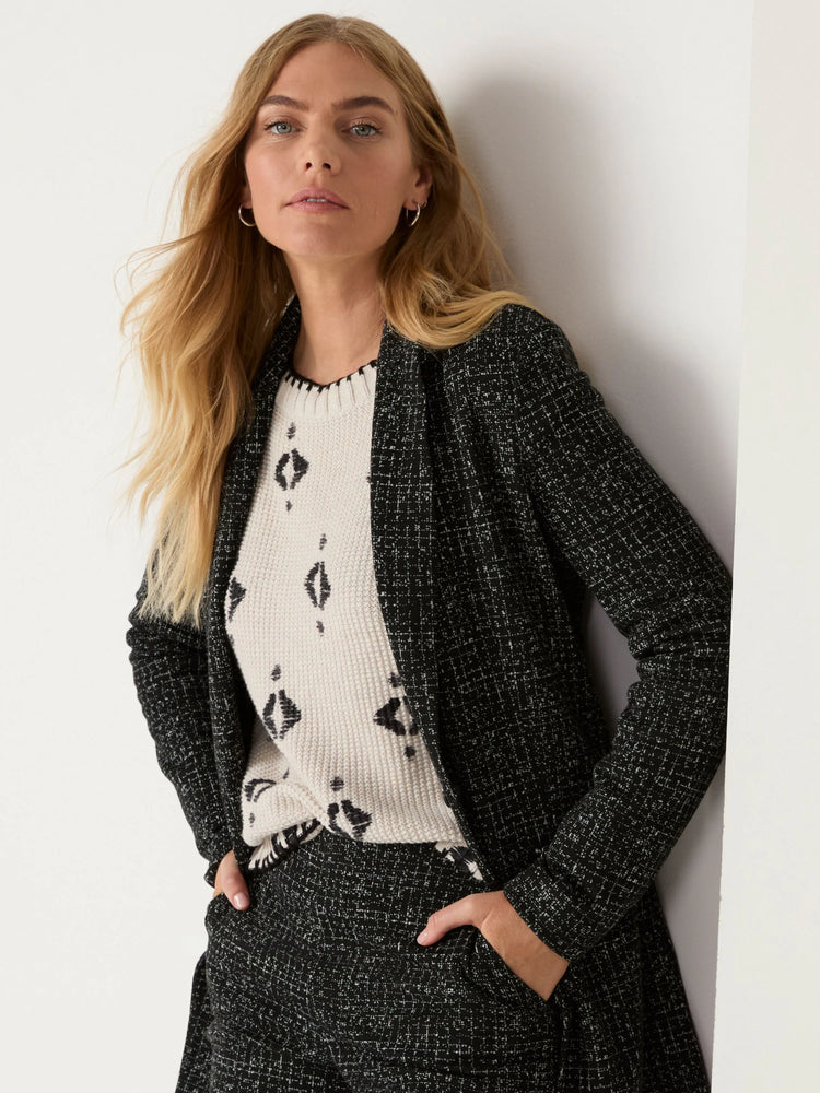 Cream sweater with scattered black diamond-like patterns and a black zigzag trimmed crew neck.