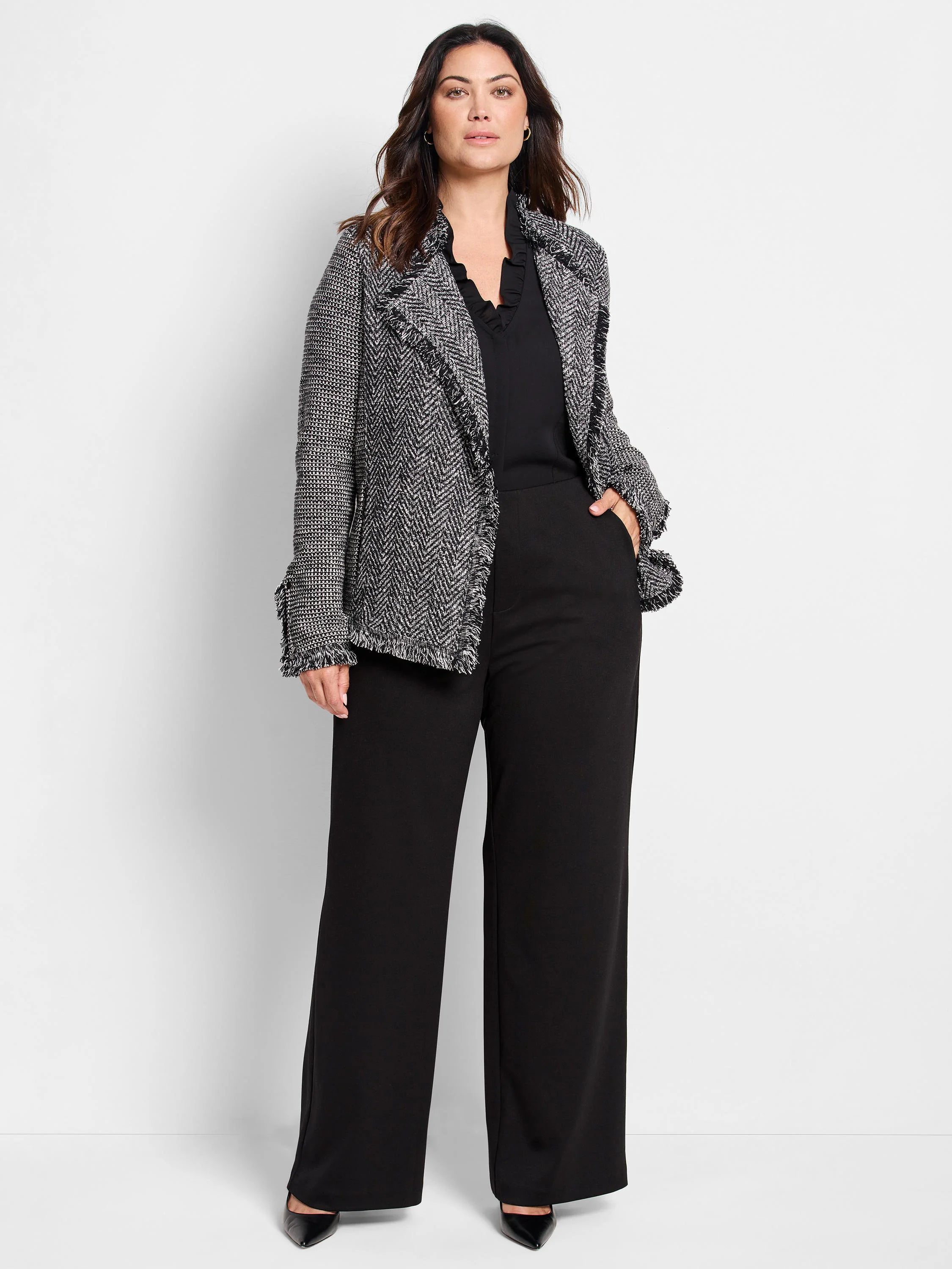 Black and white tweed-knit jacket with fringe along lapels, front opening, and cuffs.