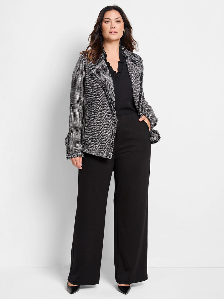 Black and white tweed-knit jacket with fringe along lapels, front opening, and cuffs.