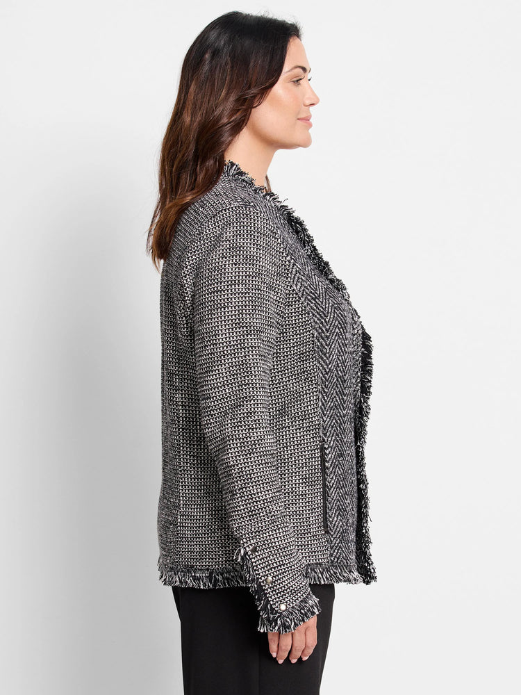 Black & white mixed knit jacket with fringe trim on open front, cuffs, and hem. Features chevron knit panels.