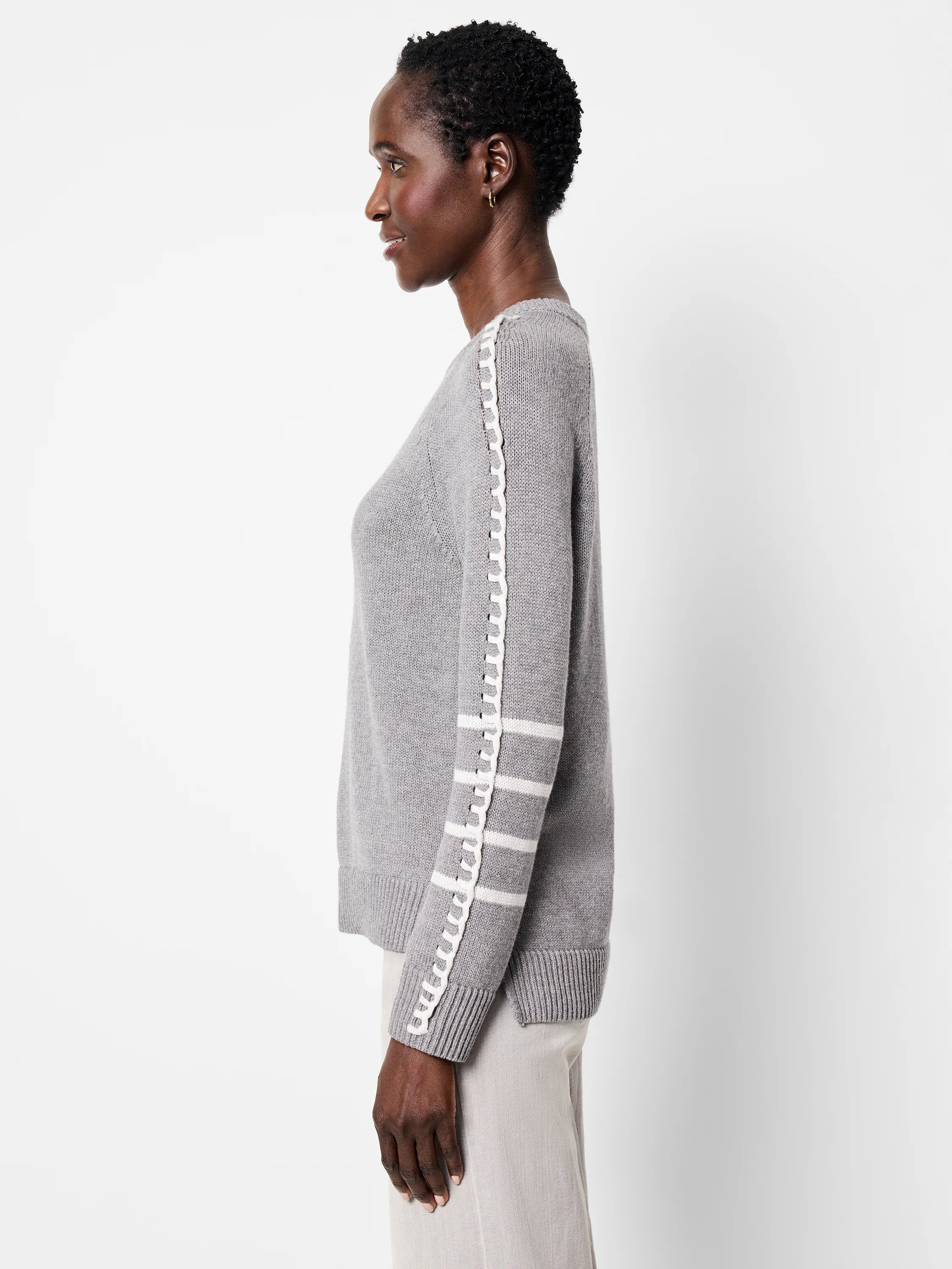 Light grey sweater with white braided trim down the sleeve seam and three white stripes on the upper arm.