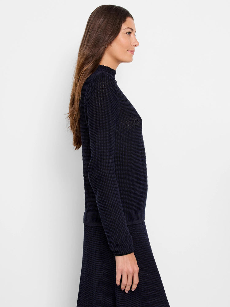 Dark blue textured pixel knit sweater with a ruffled mock neck and long sleeves.