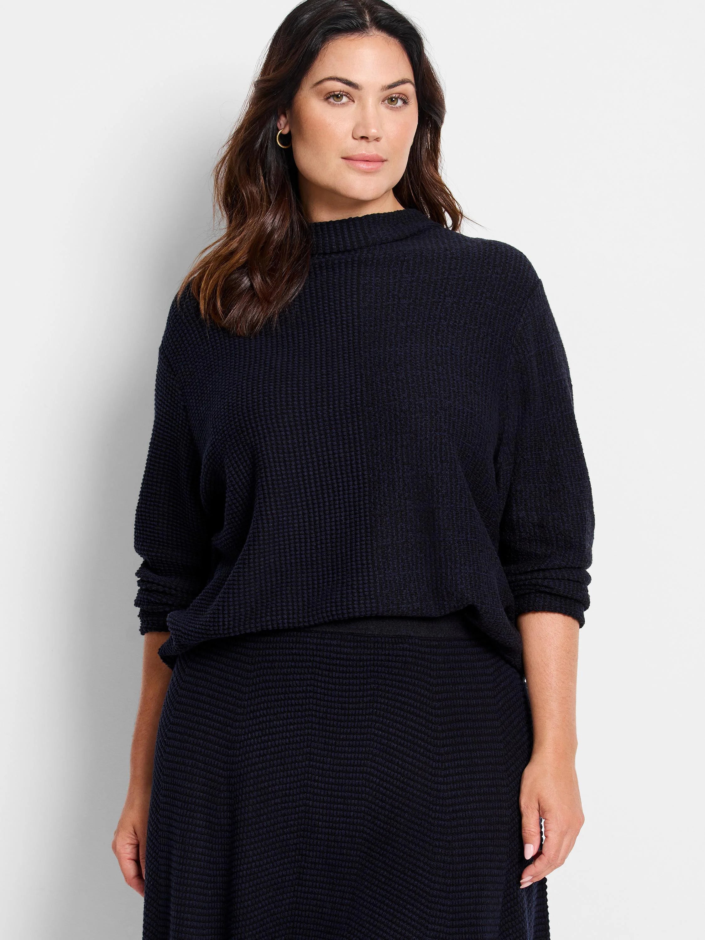 Dark navy pixel knit sweater on a model. Features a mock neck, relaxed fit, and a textured small grid pattern.