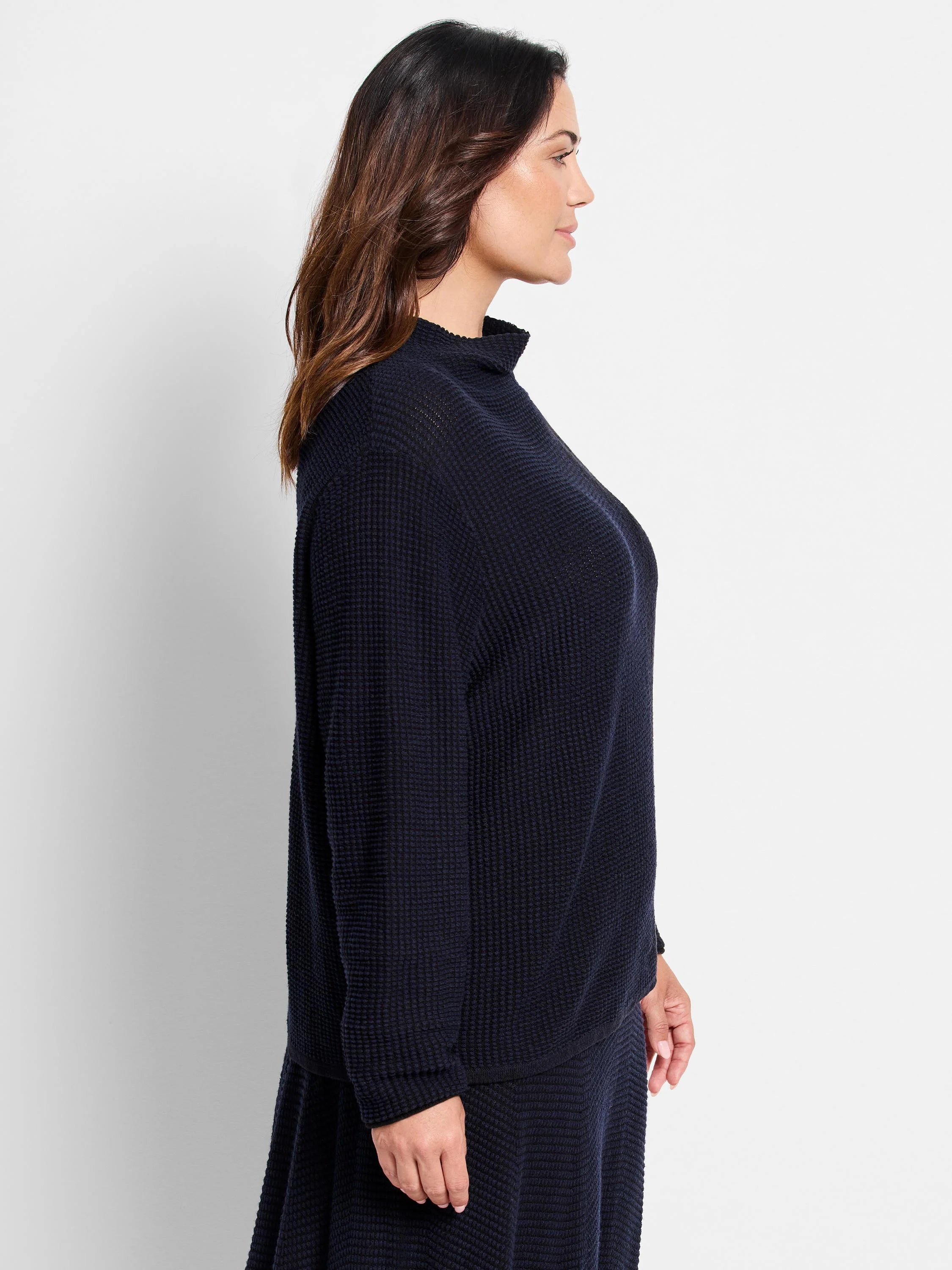 Dark navy blue, waffle-knit sweater; mock neck, long sleeves, slightly A-line shape.
