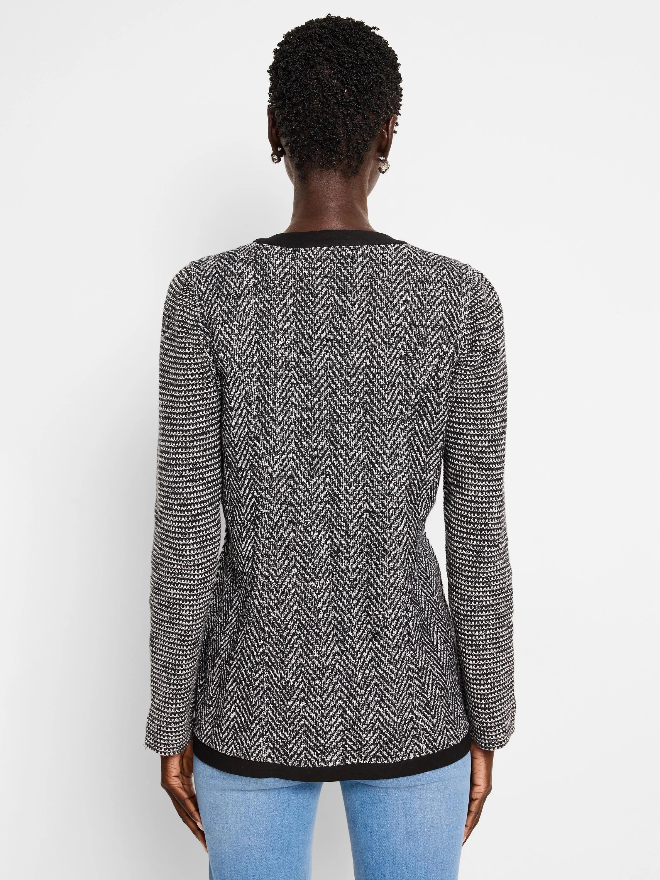 Black and white herringbone knit jacket with a black bottom band. Long sleeves.