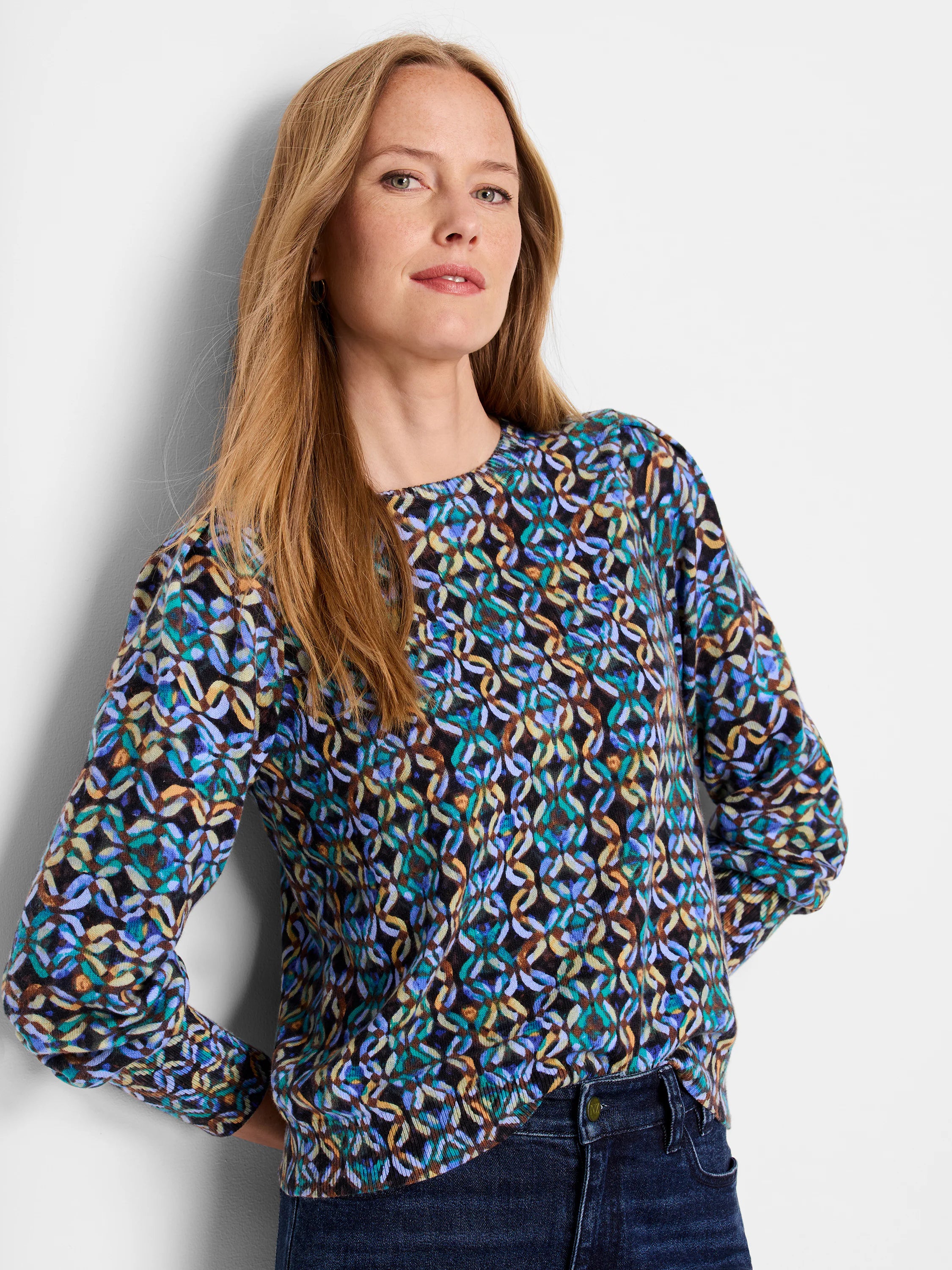 Women's long-sleeve sweater. Dark background with teal, purple, brown, and beige abstract pattern. Crew neck.