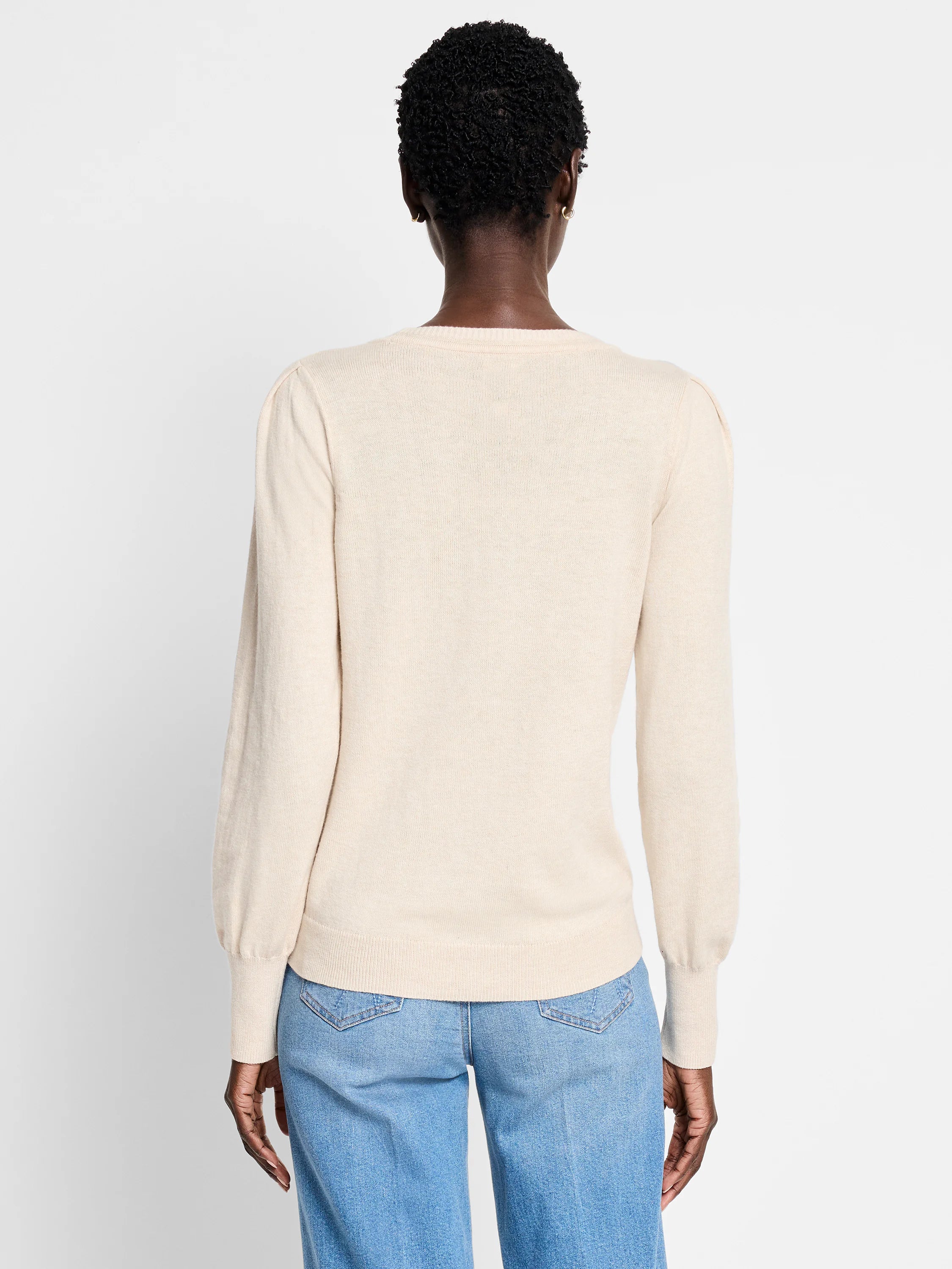 Light beige knit sweater, back view. Subtle puffed shoulders, long ribbed cuffs, round neck, and ribbed hem.