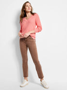 Coral pink V-neck sweater with a visible waffle stitch texture and ribbed cuffs.