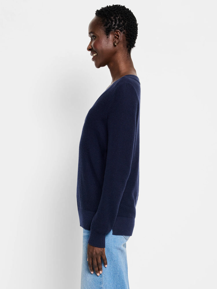 Model wearing a navy blue, relaxed fit, waffle stitch V-neck sweater.