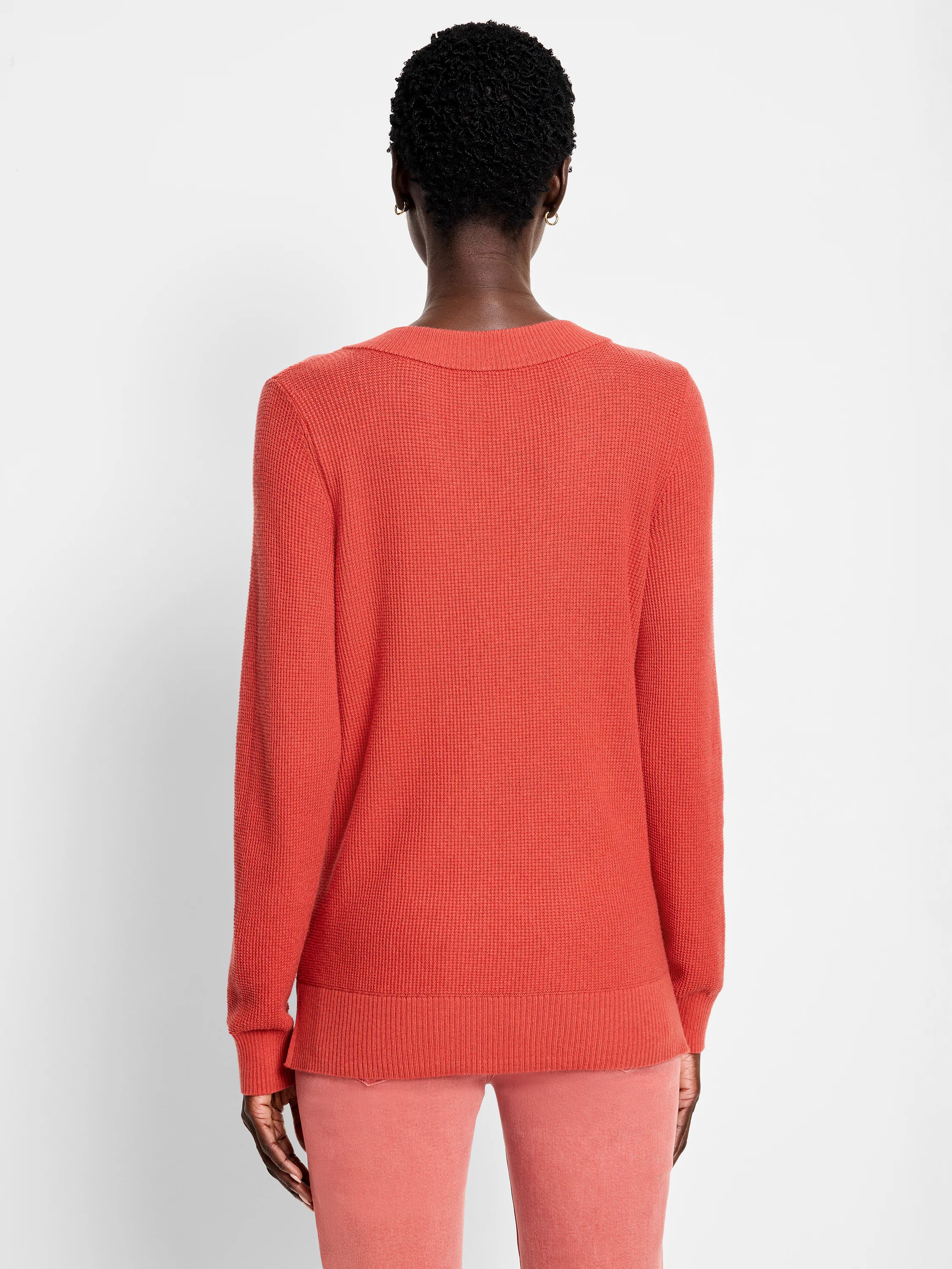 Back view of a burnt orange waffle stitch sweater with long sleeves & ribbed hem on a model.