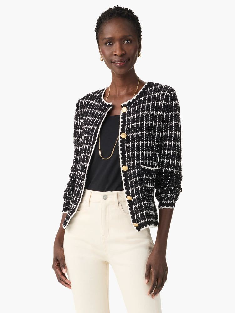 Black and white tweed jacket with gold buttons, elbow-length sleeves, and a patch pocket.