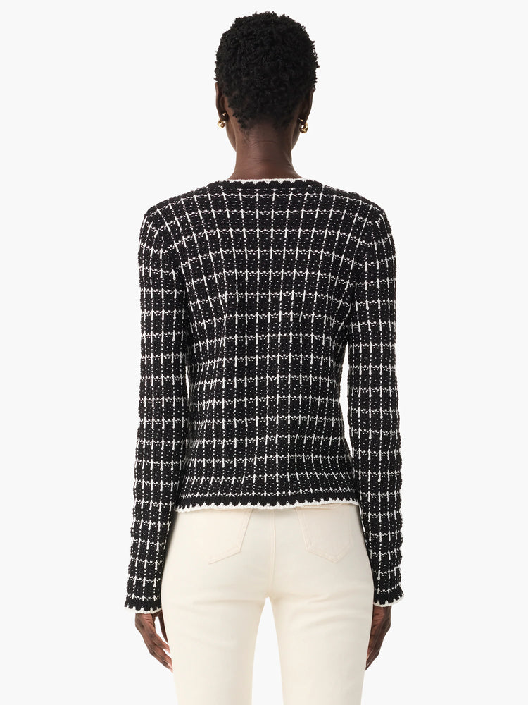 Black and white checkered tweed jacket. Long sleeves, fitted. The sweater has a textured appearance.