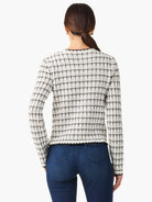 Off-white sweater jacket with black grid pattern, long sleeves, and dark trim.