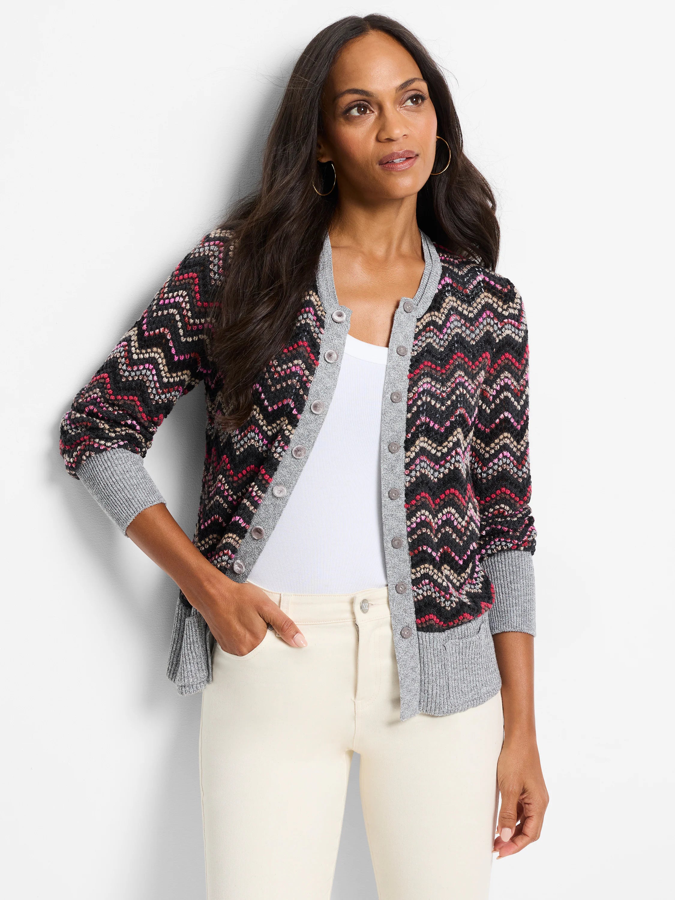 Zigzag patterned cardigan. Black background with pink, beige, and gray wavy stripes. Gray ribbed cuffs and hem. Button...