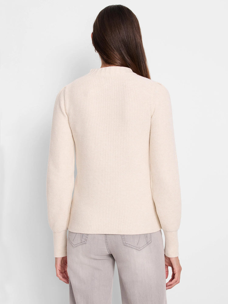 Off-white waffle-knit sweater, long sleeves, slightly puffed shoulders.