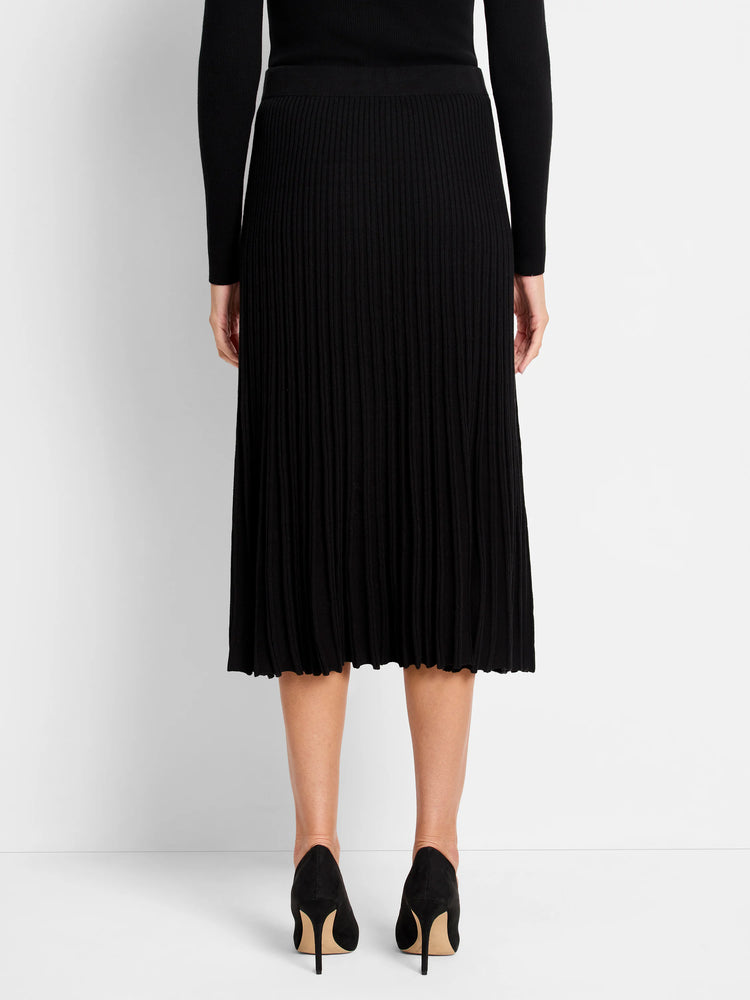 Black ribbed sweater skirt. Midi length, A-line shape, with a wavy knit hem. Model shown from behind.
