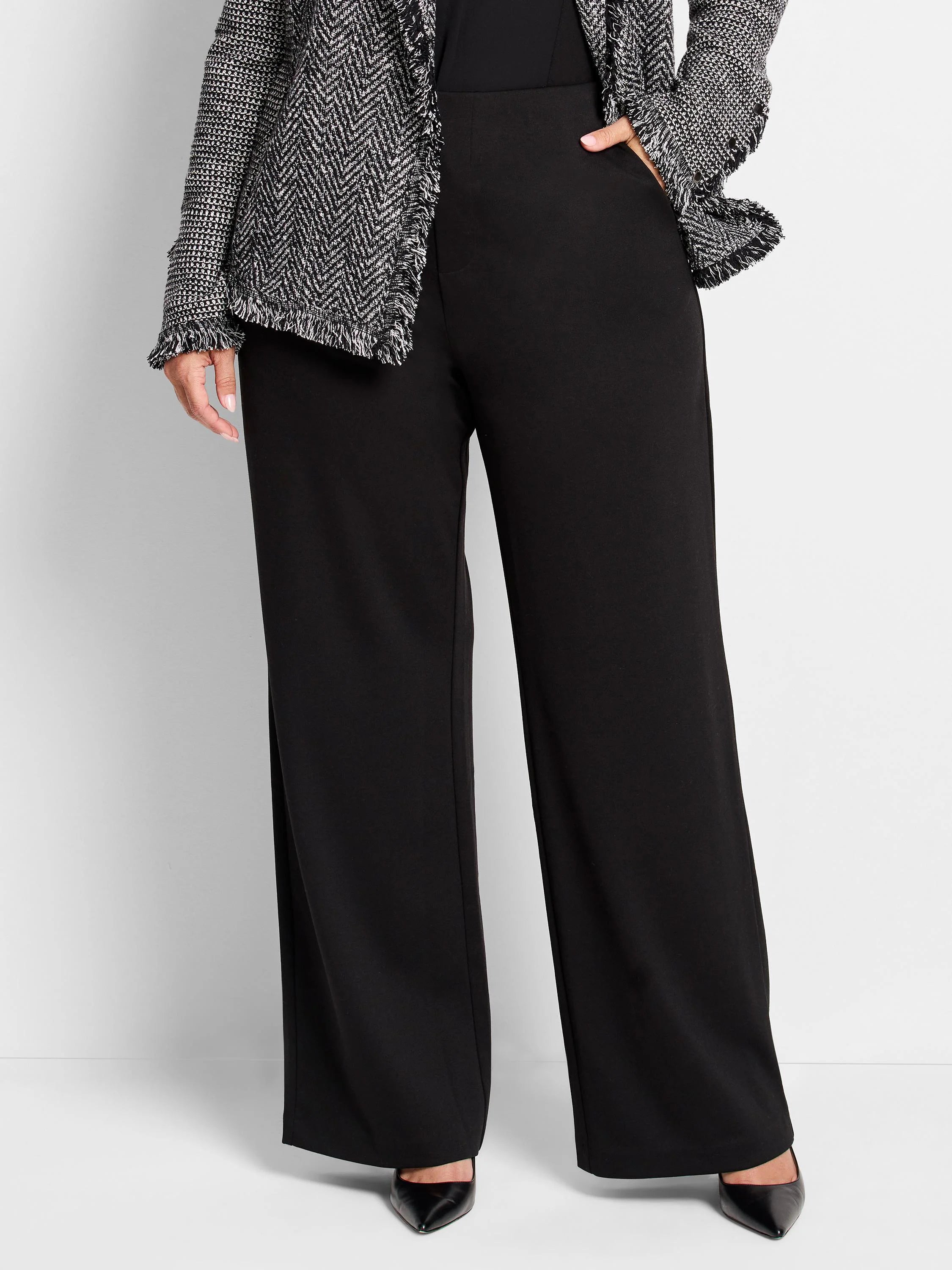 Black wide-leg pants; high waist; model also wears a black and white patterned jacket.