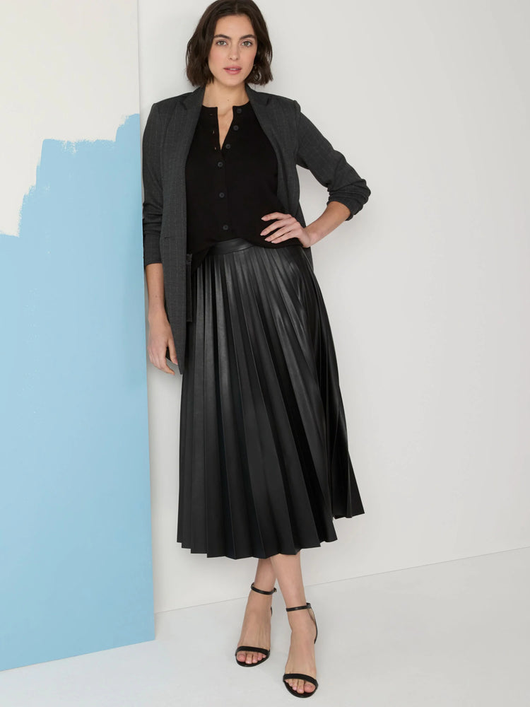 Black faux leather midi skirt with pleats. Model wears it with a black top and gray jacket.
