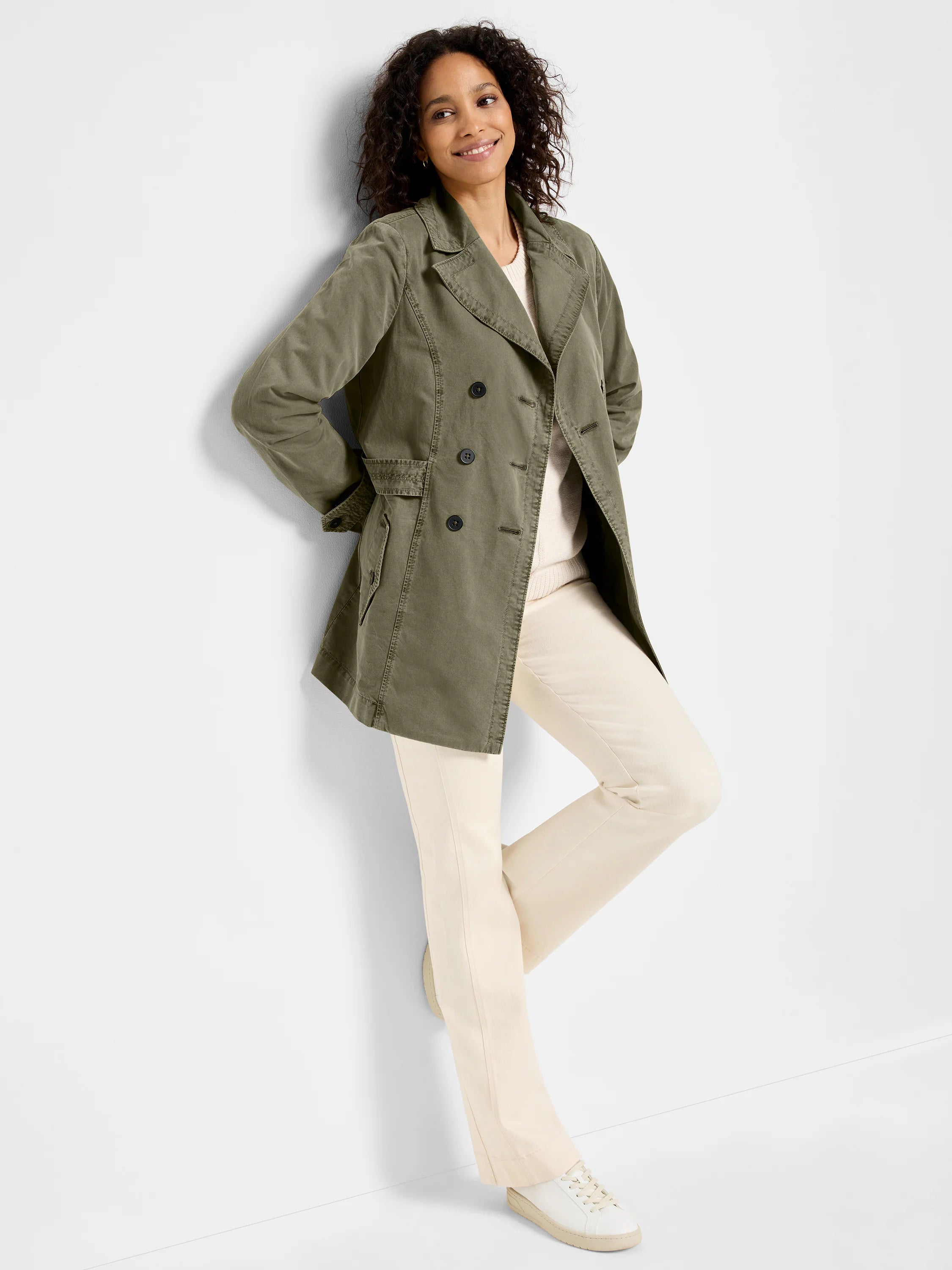 Olive green peacoat, double-breasted, belted. Model wears off-white pants & shoes.