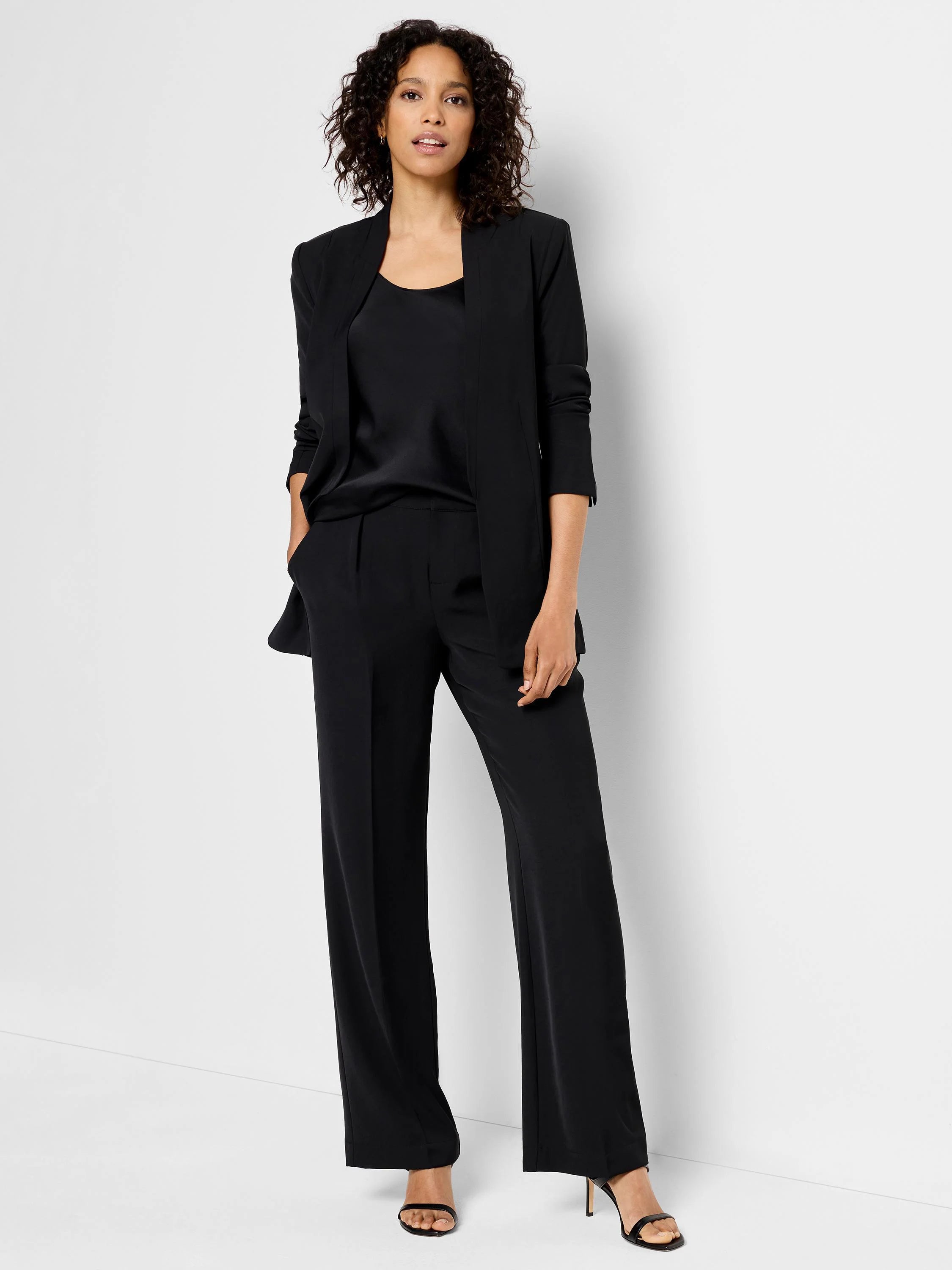 Black open blazer, three-quarter sleeves, worn over black camisole and wide-leg trousers. Model wears black heels.