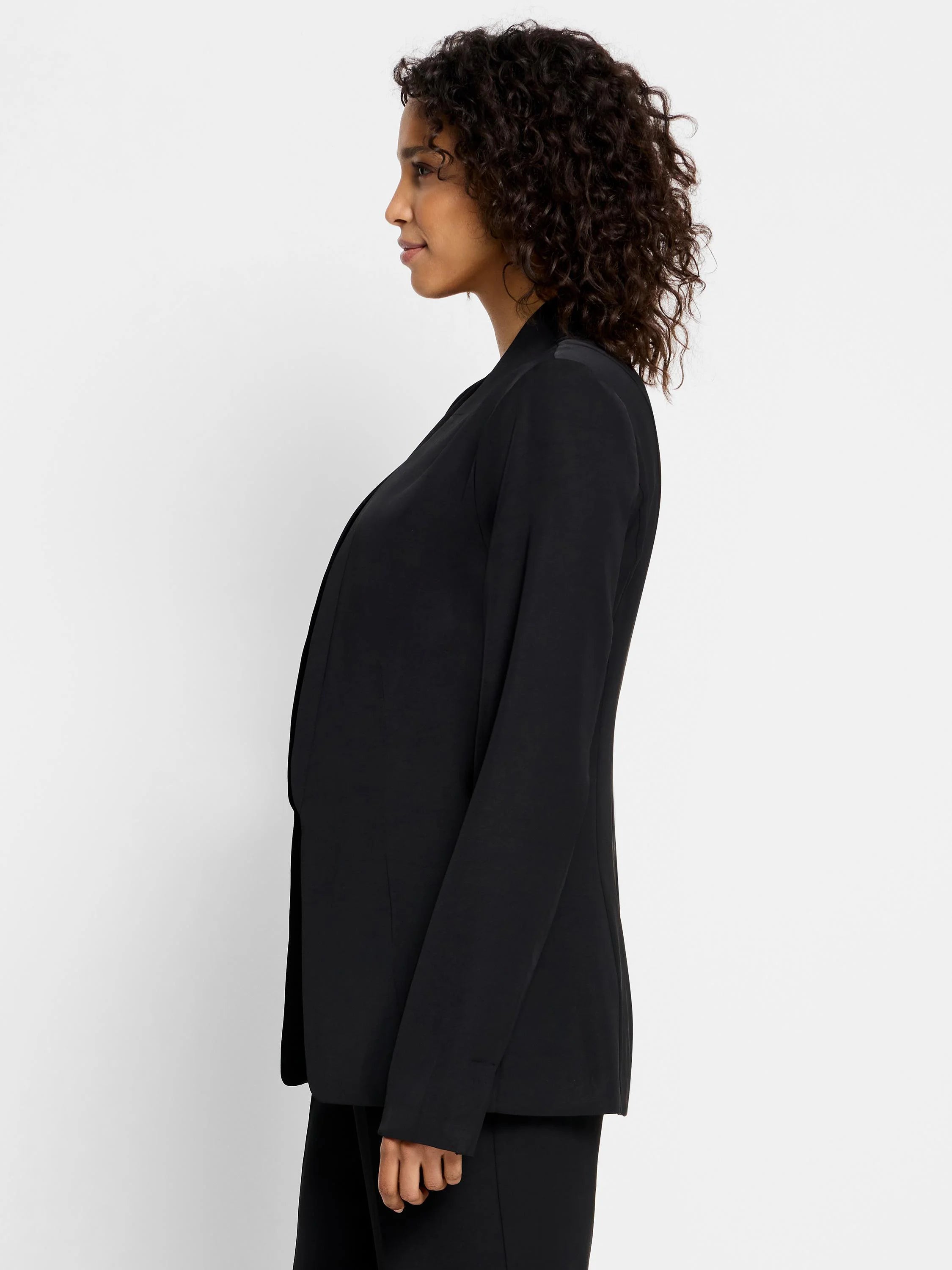 Black open blazer, long sleeves, collared. Side profile view.