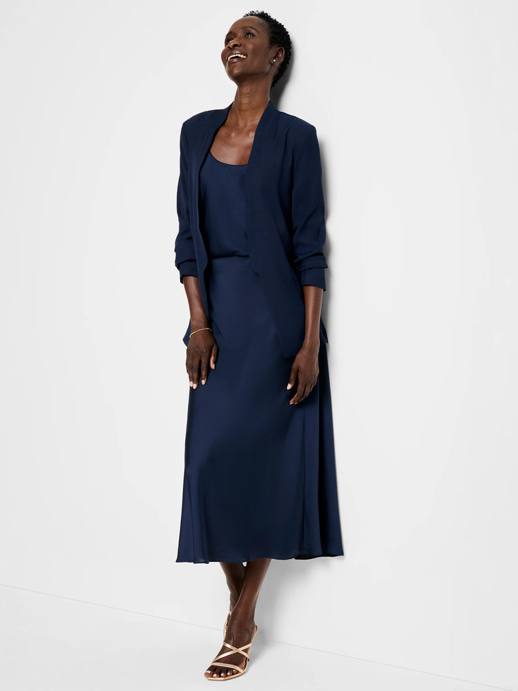 Navy blue blazer and midi skirt; open collar; three-quarter sleeves.