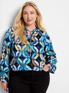 Long-sleeve, blue, teal, and beige patterned top with keyhole neckline and tie.  Features an abstract wavy design on a...
