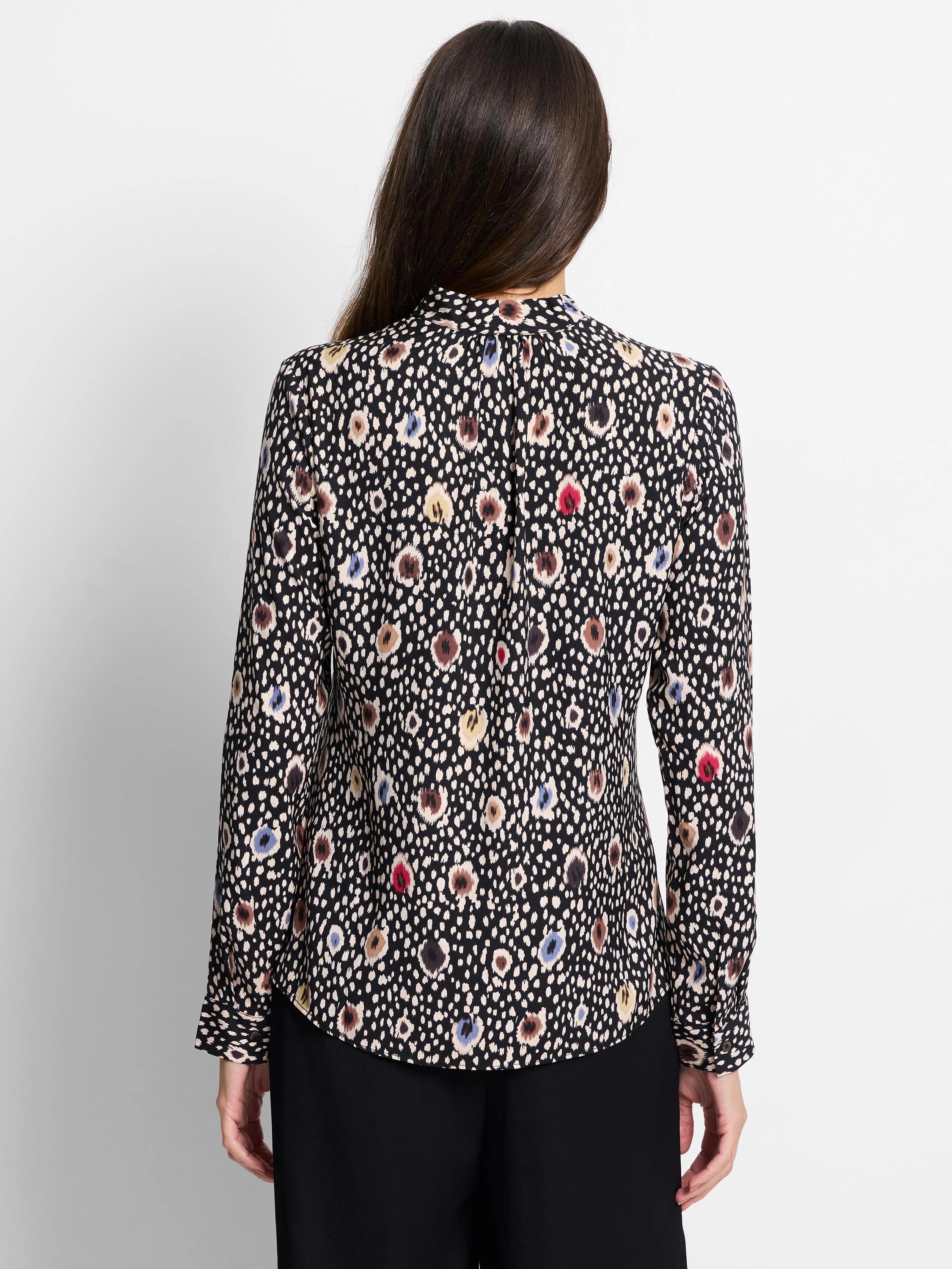 Black long-sleeve top with multicolored spotted pattern. Beige, brown, blue, and red spots on a dark background.