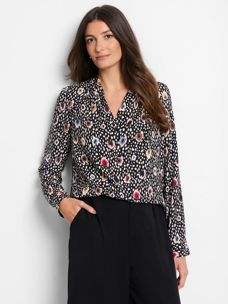 Black top with multicolored spotted pattern; beige, brown, blue, and red spots. Long sleeves, V-neck.