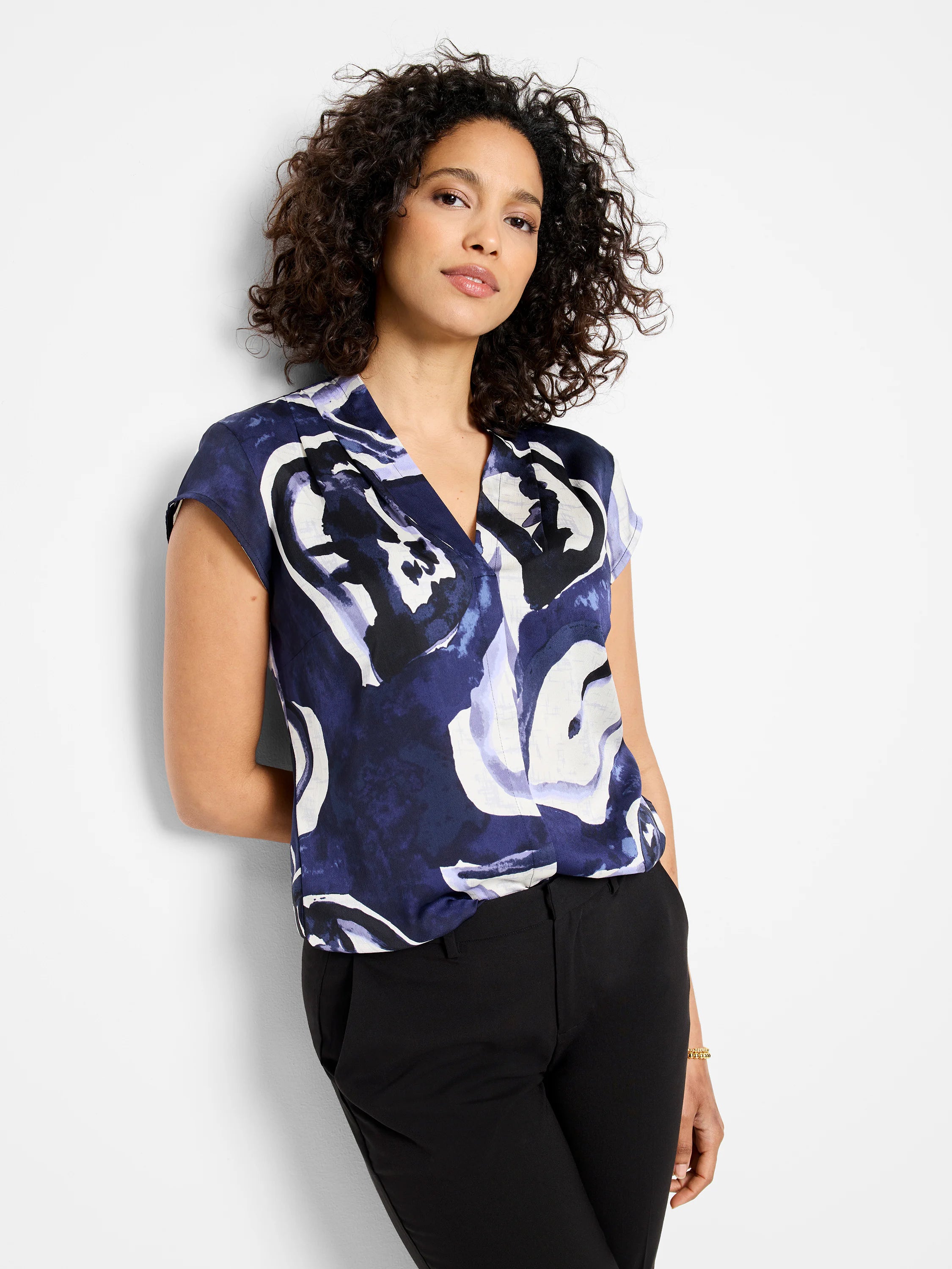 Short-sleeved v-neck blouse. Dark blue, purple, and off-white abstract watercolor vine print.