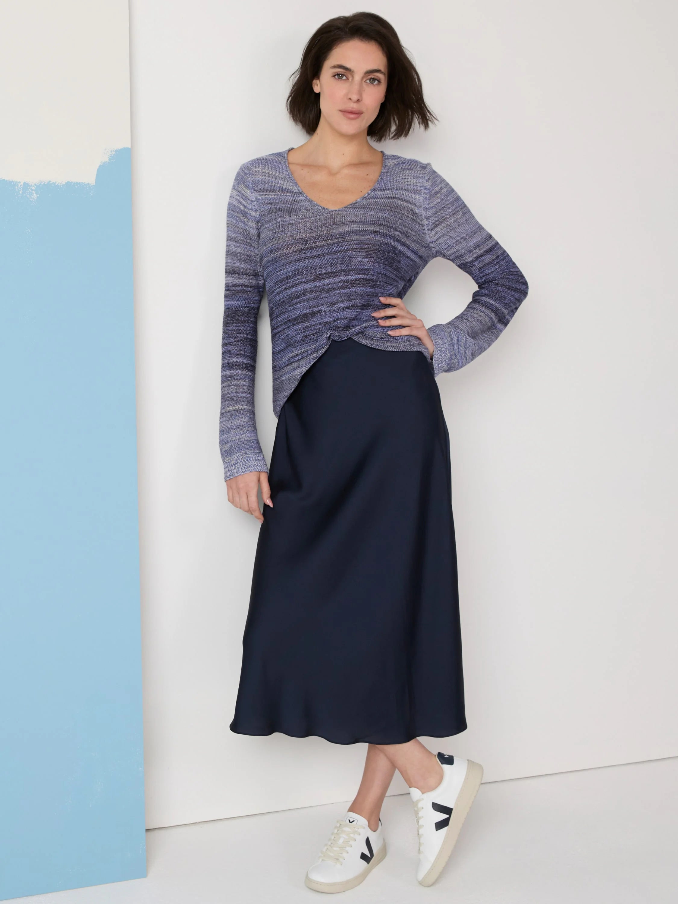 Dark navy blue midi slip skirt. Model wears a blue ombre sweater and white sneakers.